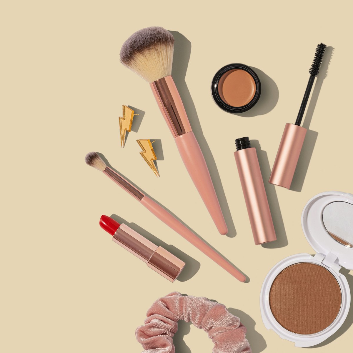 Makeup brushes and cosmetics arranged on a beige background